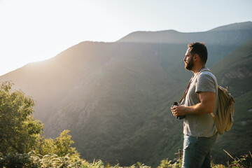 young man looking through binoculars on a mountain at sunset
