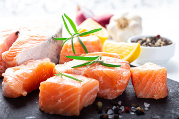 Fresh raw salmon fillet on black cutting board with lemon and spices. Healthy food concept. Close up view
