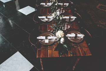 Fototapeta na wymiar Wedding banquet, serving wooden table with silver plates and decorated with flowers