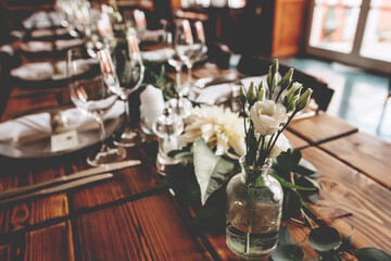 Wedding banquet, serving wooden table with silver plates and decorated with flowers