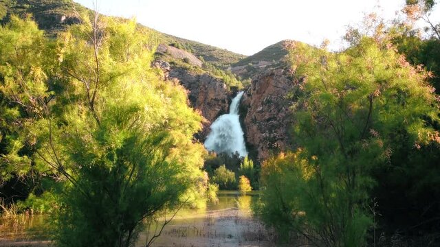 Sunset on a mountain lake watching a waterfall. Great waterfall in Spain. 