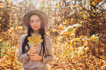 Fototapeta na wymiar Portrait of a girl in a hat in an autumn park, a woman walks in the woods at sunset