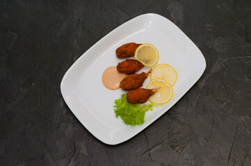 Crab claws fried in batter with lemon, lettuce and tasty sweet and sour sauce. Festive dish of Italian cuisine