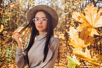 Portrait of a girl in a hat in an autumn park, a woman walks in the woods at sunset