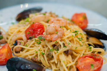 Spaghetti pasta with shrimp, mussels, tomatoes and cheese, close-up, side view. Tasty, traditional food Italians