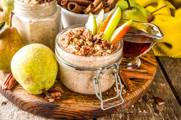 Sweet and spicy autumn breakfast oats recipe, Homemade pear and cinnamon overnight oatmeal with spices and yogurt, wooden background copy space