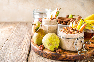 Sweet and spicy autumn breakfast oats recipe, Homemade pear and cinnamon overnight oatmeal with spices and yogurt, wooden background copy space