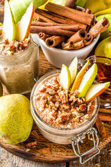 Sweet and spicy autumn breakfast oats recipe, Homemade pear and cinnamon overnight oatmeal with spices and yogurt, wooden background copy space