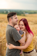 Father, mother and their little son have fun together in a wheat field.