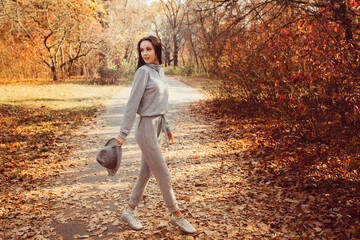 Portrait of a girl in a hat in an autumn park, a woman walks in the woods at sunset