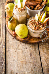 Sweet and spicy autumn breakfast oats recipe, Homemade pear and cinnamon overnight oatmeal with spices and yogurt, wooden background copy space