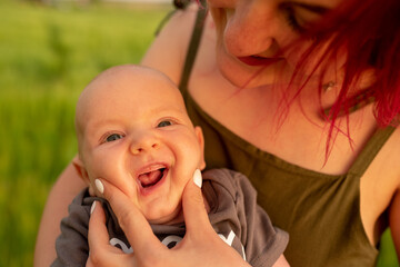 Mom holds her little son's toothless mouth open.