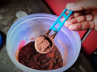 chocolate powder in tea spoon ready to add in milk