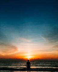 Naklejka na ściany i meble silhouette of a man on the beach at sunrise
