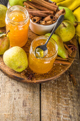 Homemade sweet and spicy pear jam. Different glass jars with pear jam, on wooden background with fresh pears and spices