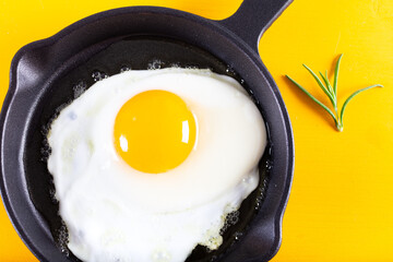 Fried egg. Close up view of the fried egg on a frying pan on yellow background.