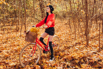 Obraz na płótnie Canvas Portrait of a pretty girl with a red bike in the autumn forest
