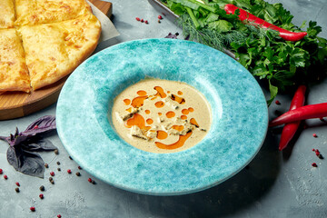 A dish of Georgian chicken fillet in nut sauce or Satsivi in blue plate with khachapuri. Close up