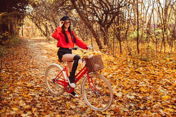 Naklejka na ściany i meble Portrait of a pretty girl with a red bike in the autumn forest