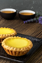 Two Delicious freshly baked egg tarts served with Chinese tea