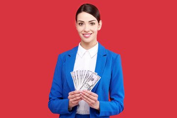 Girl holding money, business woman with stack of dollars, female in blue suit in red isolated background