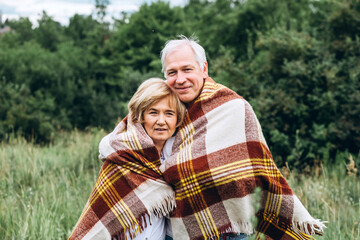 mature couple is walking with dog in park. Elderly couple resting in nature with a dog. Full-length portrait of an elderly man and woman in white shirts and jeans. Stylish and modern grandparents.