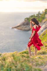 Portrait of Young Asian Woman in a beautiful red dress standing at the edge of cliff in the top mountains. Fashion model, bride or pre-wedding concept.