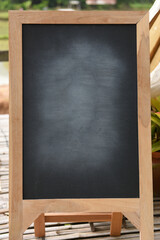 Fototapeta na wymiar Black blackboard on wooden easel rubbed out dirty chalkboard on outdoors /