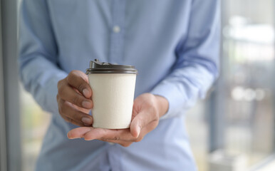 Close-up shot of Barista holding coffee cup take away in hand.