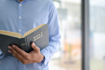 Cropped shot of A man holding the bible in hand.