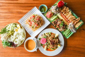 Asian Thai food top view with Thai rice noodles curry , Papaya salad , shrimp salad and Salad fish food served on wooden table setting plate /
