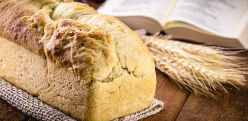 homemade bread made in the Easter and Eucharist period, called Christ bread, religious symbol, with Bible and crucifix in the background