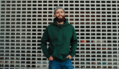 City portrait of handsome hipster guy with beard wearing green (watercolor) blank hoodie or sweatshirt with space for your logo or design. Mockup for print