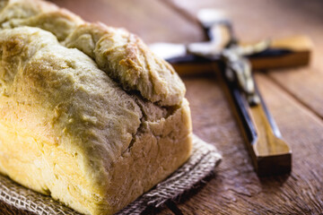 homemade bread made in the Easter and Eucharist period, called Christ bread, religious symbol, with Bible and crucifix in the background