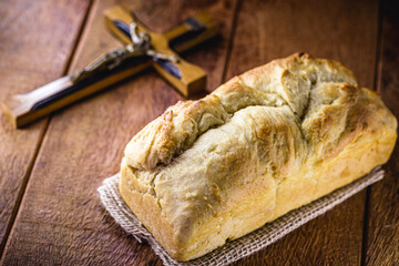 homemade bread made in the Easter and Eucharist period, called Christ bread, religious symbol, with Bible and crucifix in the background