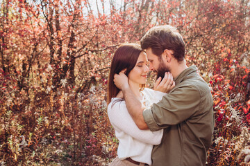 Fototapeta premium Portrait of a young couple in the autumn forest, a guy and a girl cuddling in the outdoor