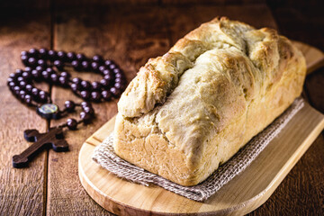 homemade bread made in the Easter and Eucharist period, called Christ bread, religious symbol, with Bible and crucifix in the background