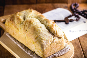 homemade bread made in the Easter and Eucharist period, called Christ bread, religious symbol, with Bible and crucifix in the background