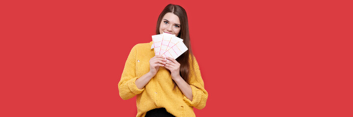 Smiling caucasian woman holding lottery tickets, isolated red background