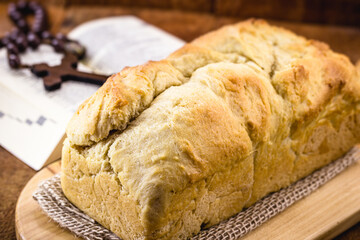 homemade bread made in the Easter and Eucharist period, called Christ bread, religious symbol, with Bible and crucifix in the background