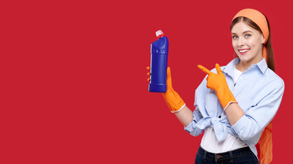 Smiling young housewife wearing casual clothes in orange latex gloves holding cleaning agent and showing finger gesture, cleaning concept