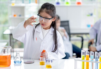 Lovely little girl enjoy and excite to examine the color chemical in laboratory by using dropper with day light. Concept of good practice and education of science for children support their learning.