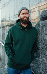 City portrait of handsome hipster guy with beard wearing green (watercolor) blank hoodie or...