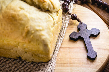 homemade bread made in the Easter and Eucharist period, called Christ bread, religious symbol, with Bible and crucifix in the background