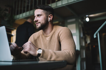 Cheerful young man listening to music in cafe