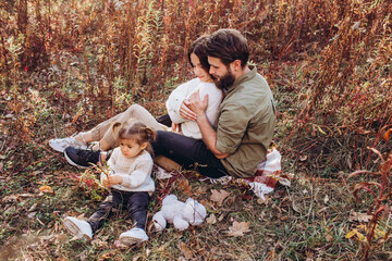 Naklejka na ściany i meble Young parents with daughter walk in autumn park, family portrait outdoors