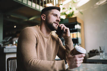 Concentrated male speaking on phone in cafe