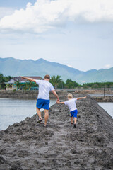 Father son walk near mountain lake, play show outstretched hands like airplane. Happy childhood....