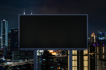 Blank black road billboard with Kuala Lumpur cityscape background at night time. Street advertising poster, mock up, 3D rendering. Front view. Concept of marketing to promote or sell idea or product.