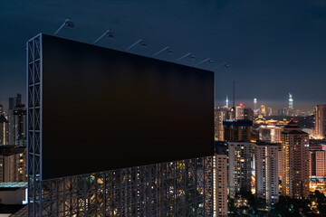 Blank black road billboard with KL cityscape background at night time. Street advertising poster, mock up, 3D rendering. Side view. The concept of marketing communication to promote or sell idea.